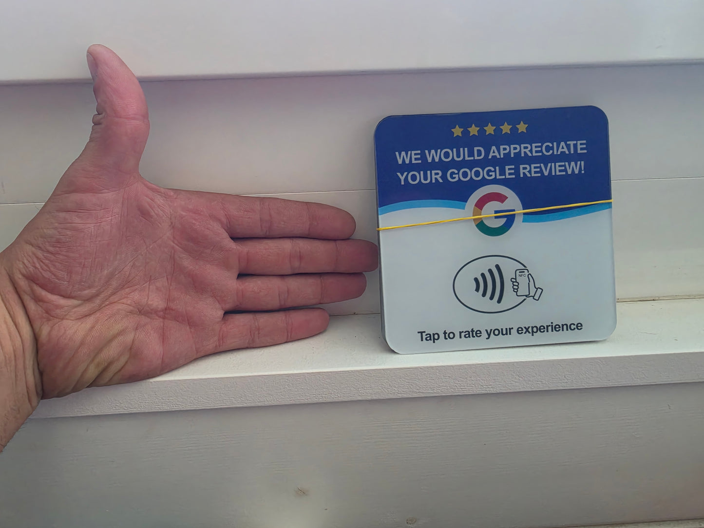Google Bewertungskarte mit NFC neben einer Hand als Grössenvergleich